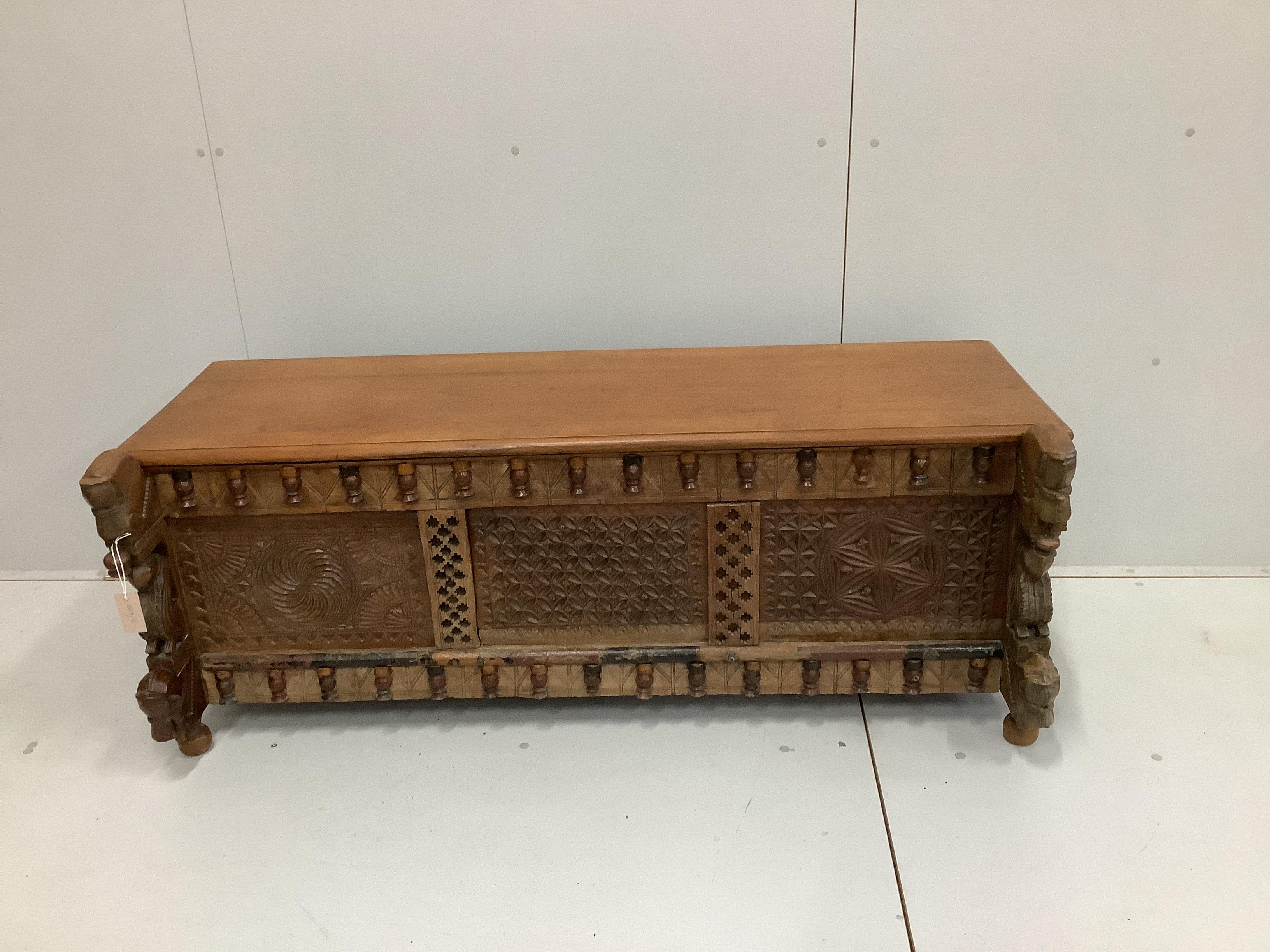 An Indian carved and panelled hardwood low chest, with figural motifs, width 148cm, depth 60cm, height 57cm.